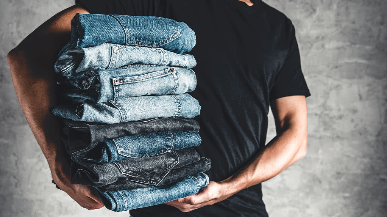 Un hombre cargando una pila de jeans.