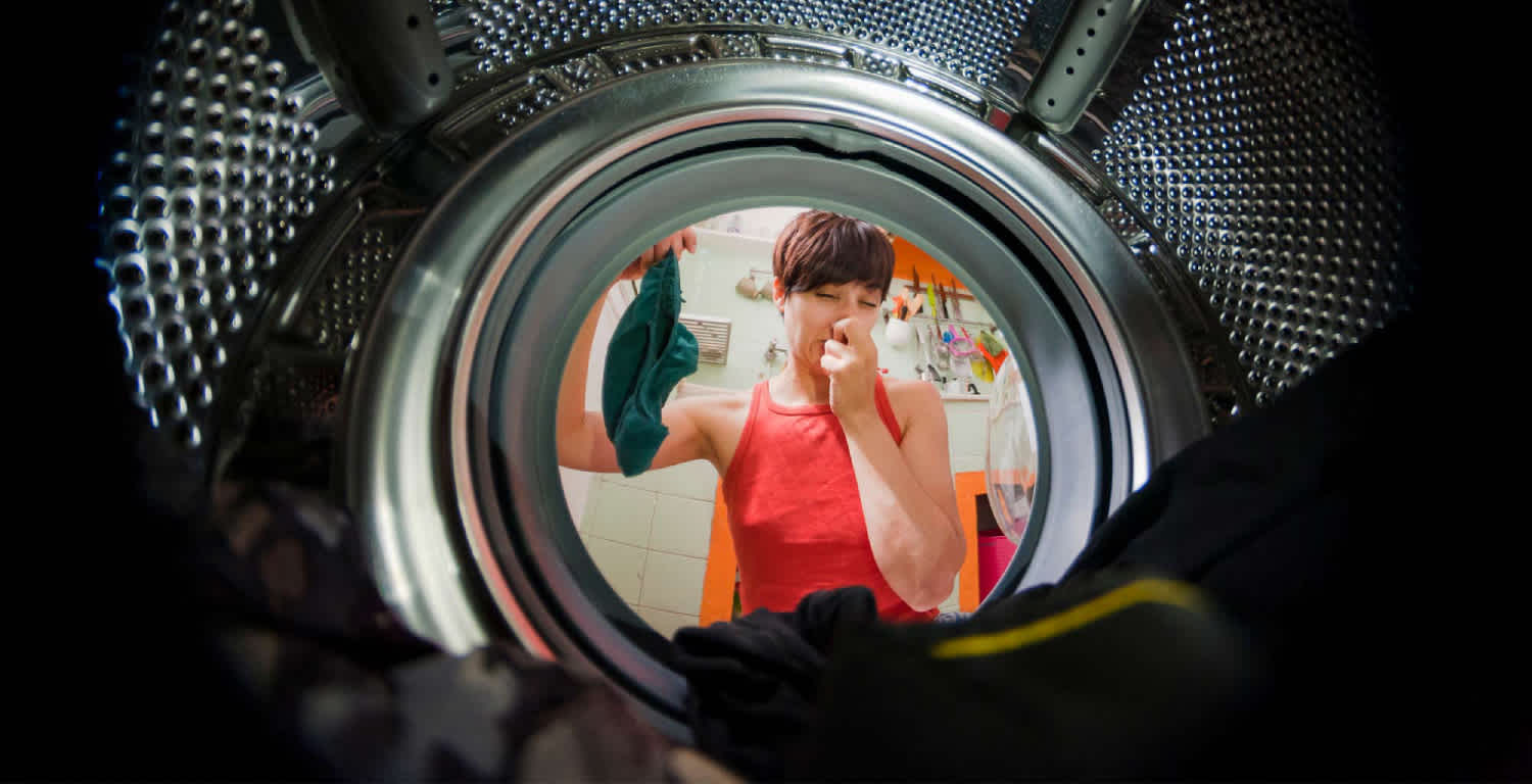 Una-mujer-sosteniendo-una-prenda-que-saco-de-la-lavadora-y-huele-mal