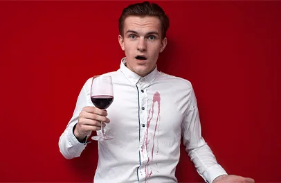 Como-quitar-manchas-de-vino Un hombre sosteniendo una copa de vino con su camisa manchada