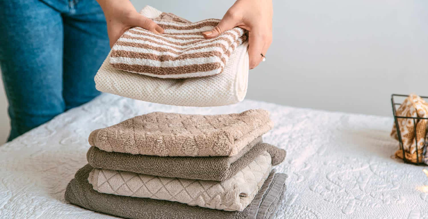 Una mujer haciendo una pila de ropa pila sobre la cama