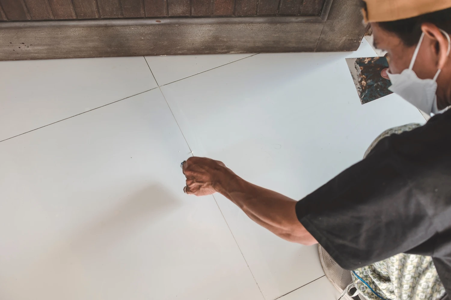 Persona instalando un piso de cerámica con sus manos.