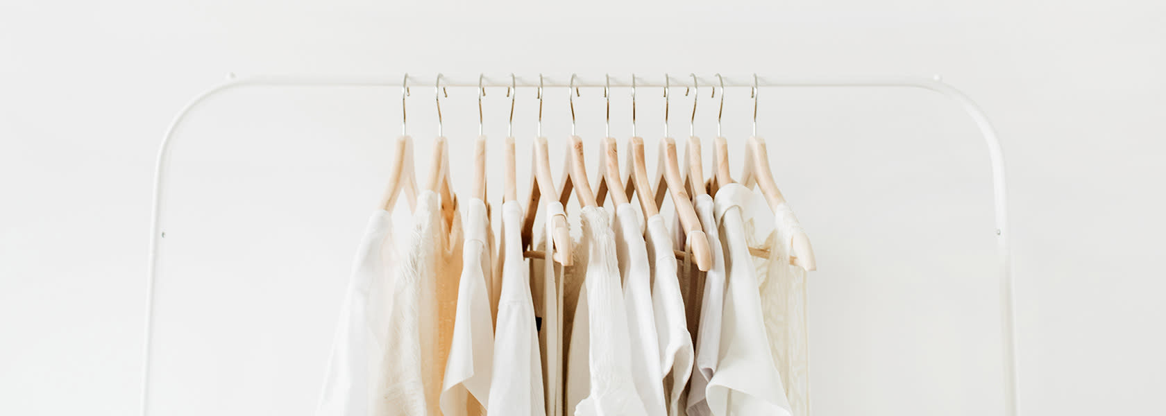 Camisas colgadas con perchas en un perchero sobre un fondo celeste.