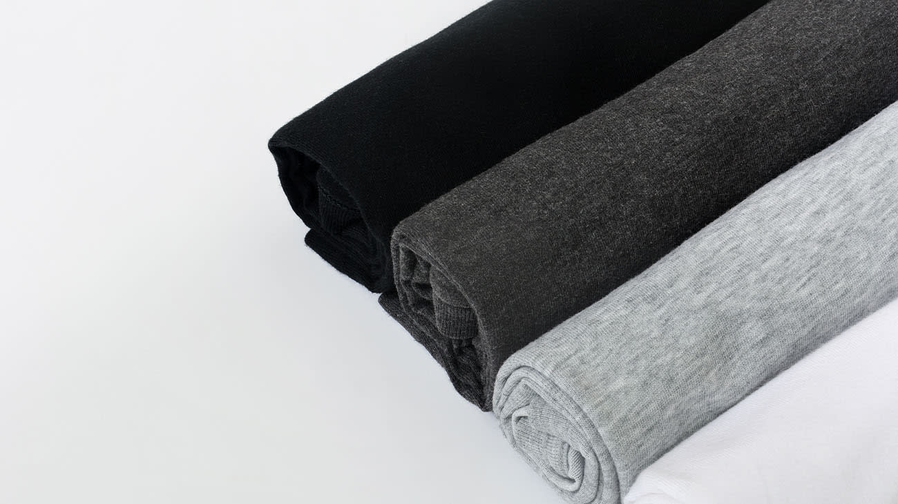 Remeras dobladas en forma de paquetito sobre un fondo blanco.