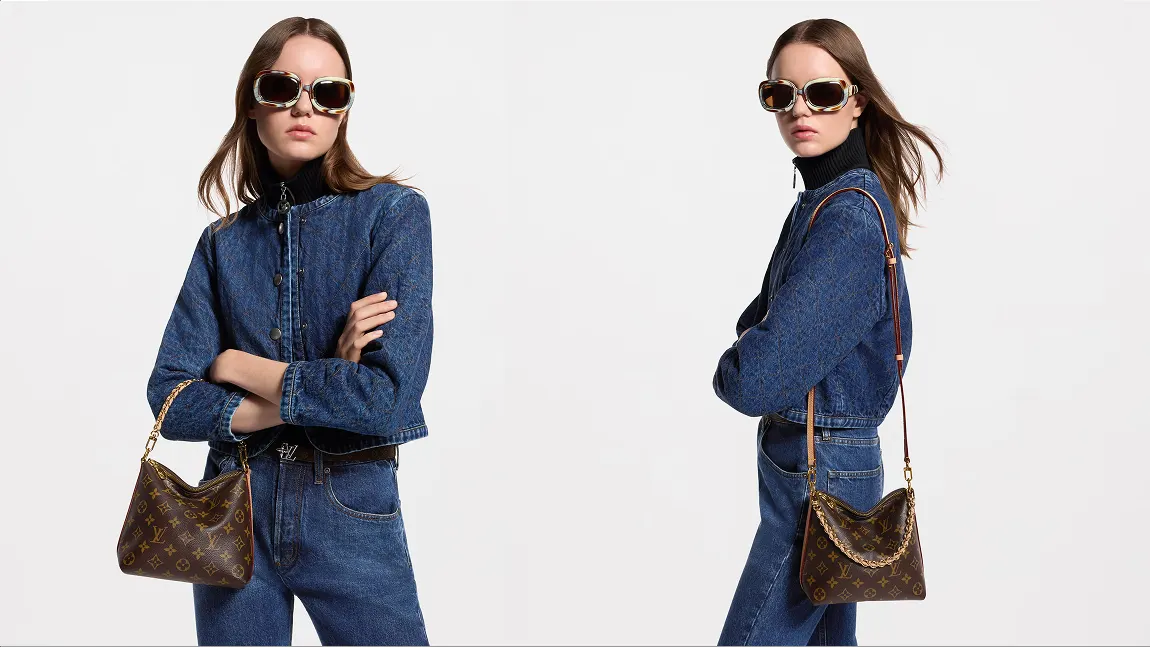 A model wearing a denim jacket and oversized sunglasses poses with a brown monogram shoulder bag featuring a gold chain strap.