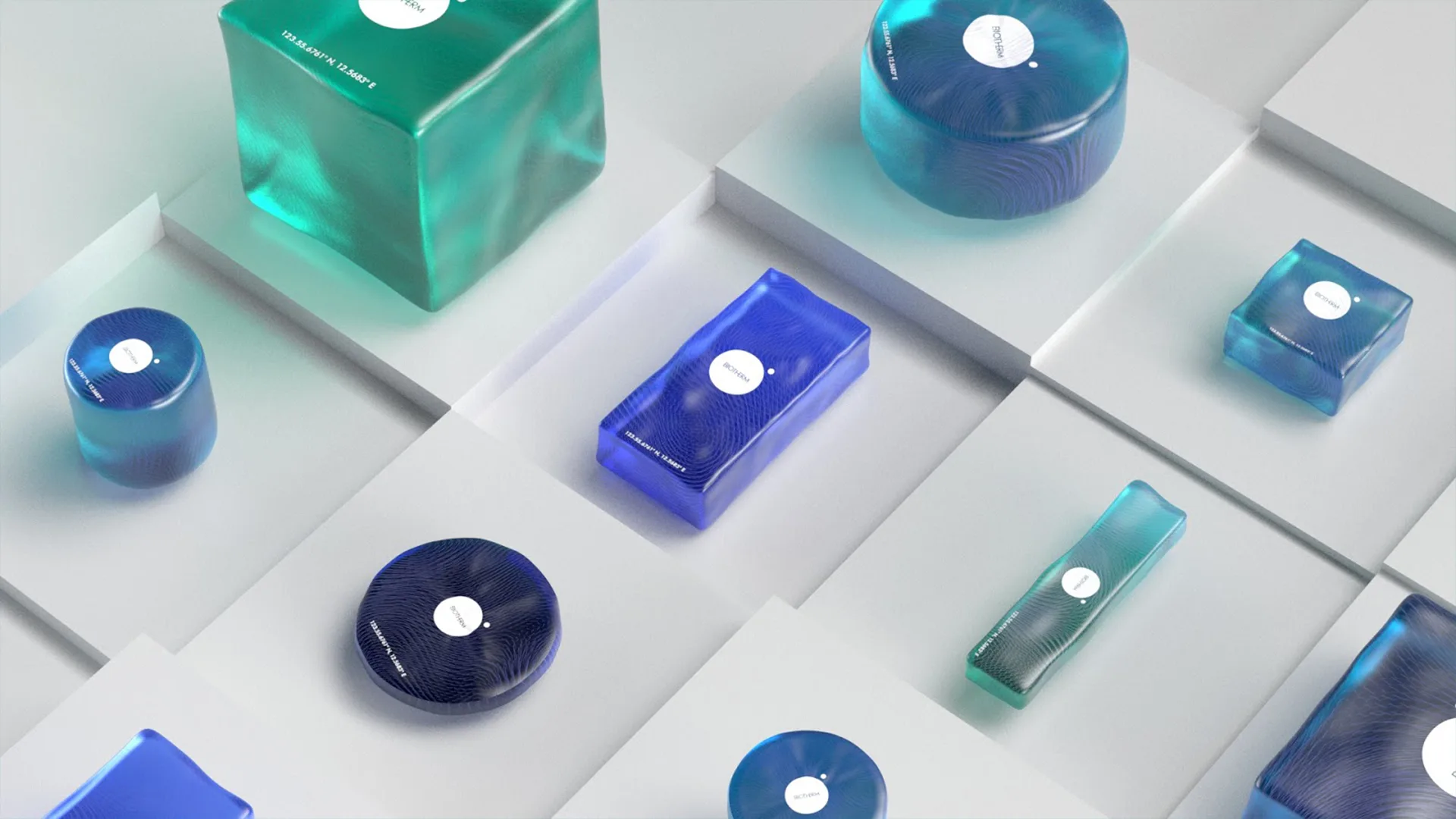 Assorted blue and green translucent geometric containers with white labels are arranged on white square platforms, creating a modern and minimalist display.