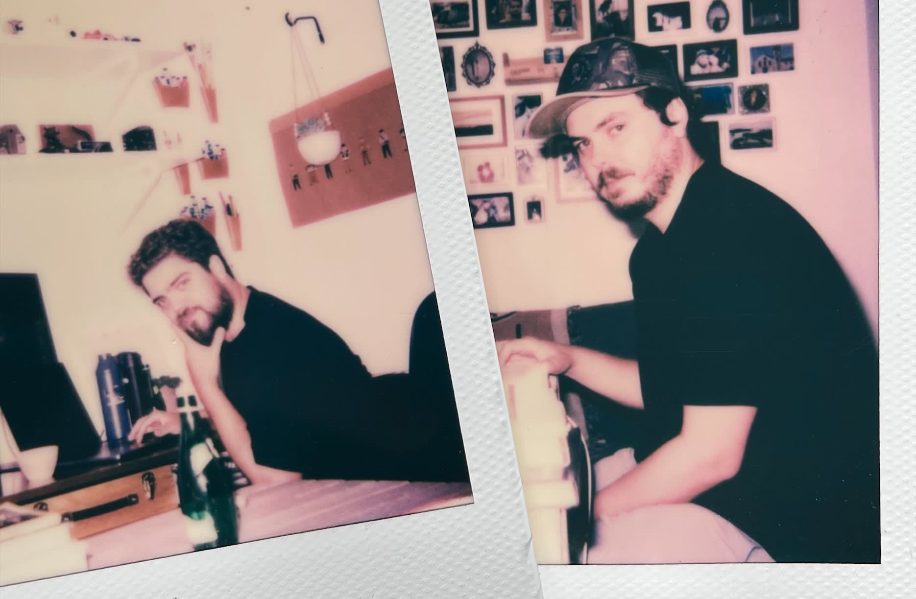 Two side-by-side Polaroid photos of a man with a beard and dark shirt indoors; in one, he is seated at a desk with a drink, and in the other, he sits sideways on a chair with framed photos on the wall behind him.