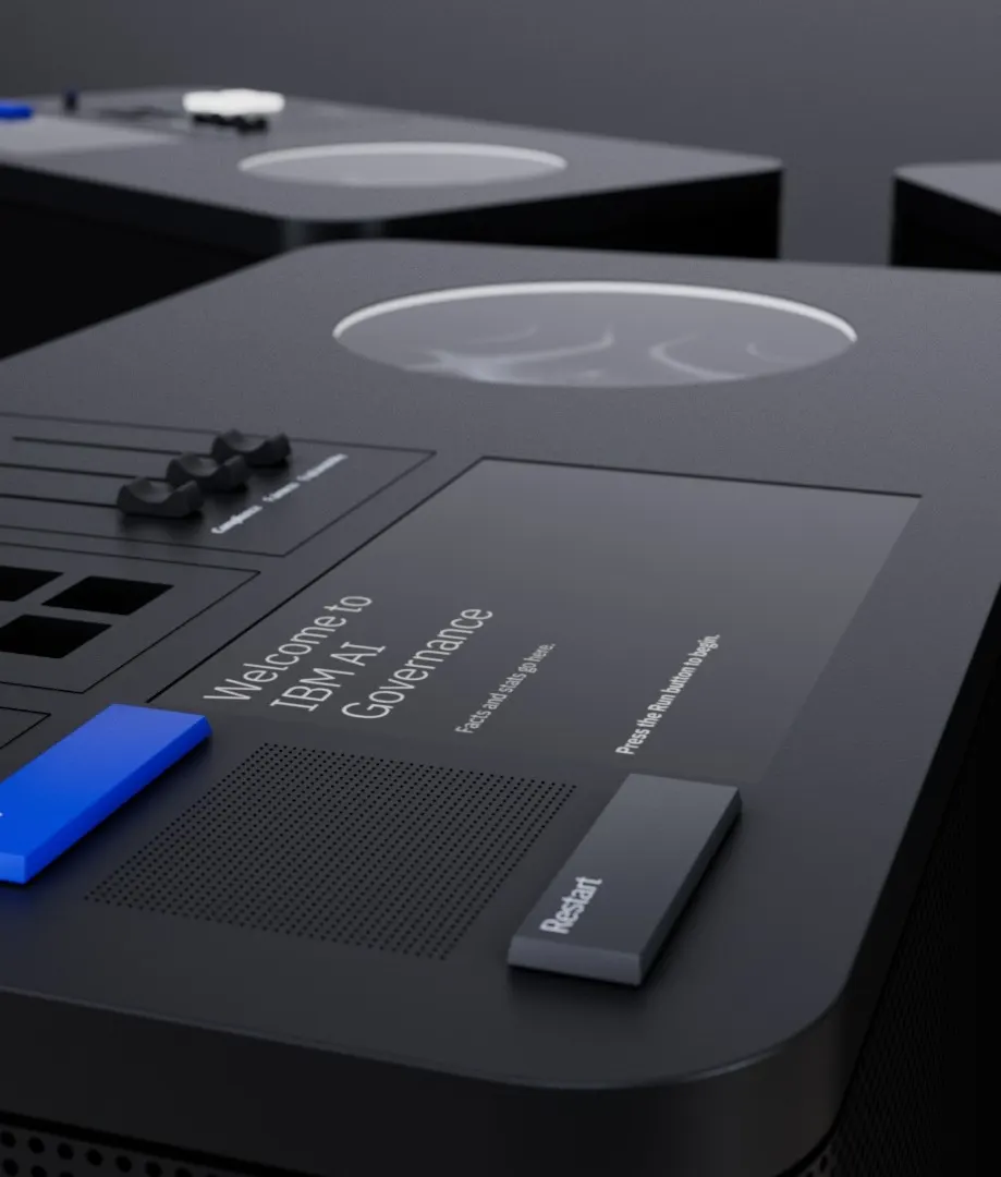 Close-up of a sleek black device with a digital display reading Welcome to IBM AI Governance. The device features several buttons, including a prominent blue one and a black one labeled Restart.