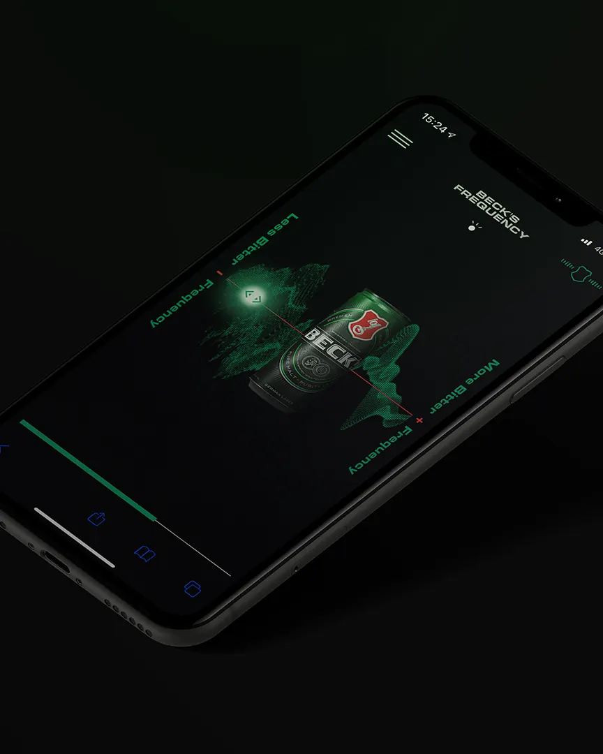 A smartphone displaying a dark-themed app screen with a Beck’s beer can, green soundwave graphics, and text reading “BEST FREQUENCY” and “MORE BECK’S + FREQUENCY.” The phone is tilted at an angle on a black background.