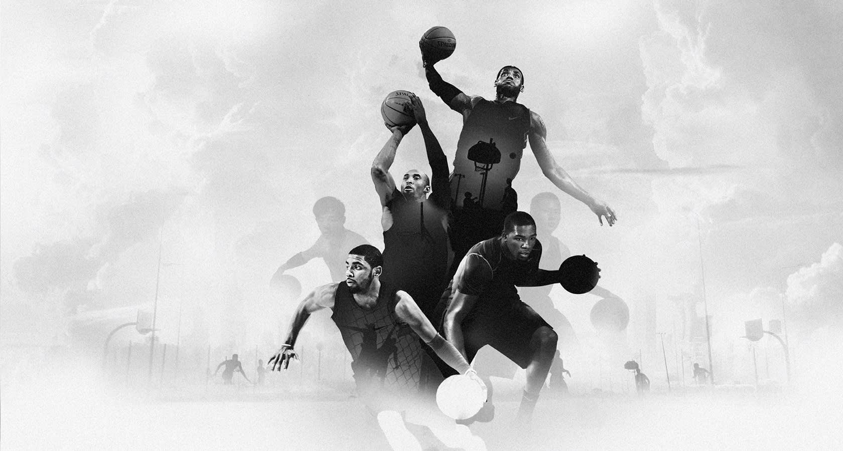 Black and white image of four basketball players in dynamic action poses, dribbling and jumping with basketballs, set against a cloudy, dreamlike outdoor background with faint silhouettes of hoops and equipment.