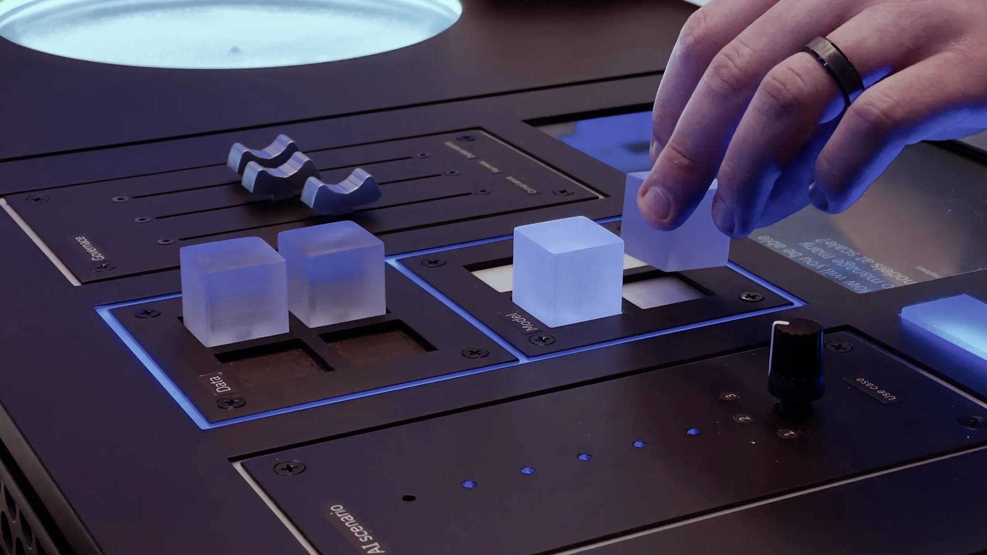 A hand adjusts translucent cube-shaped controls on a sleek, modern control panel with sliders, buttons, and blue accent lighting.