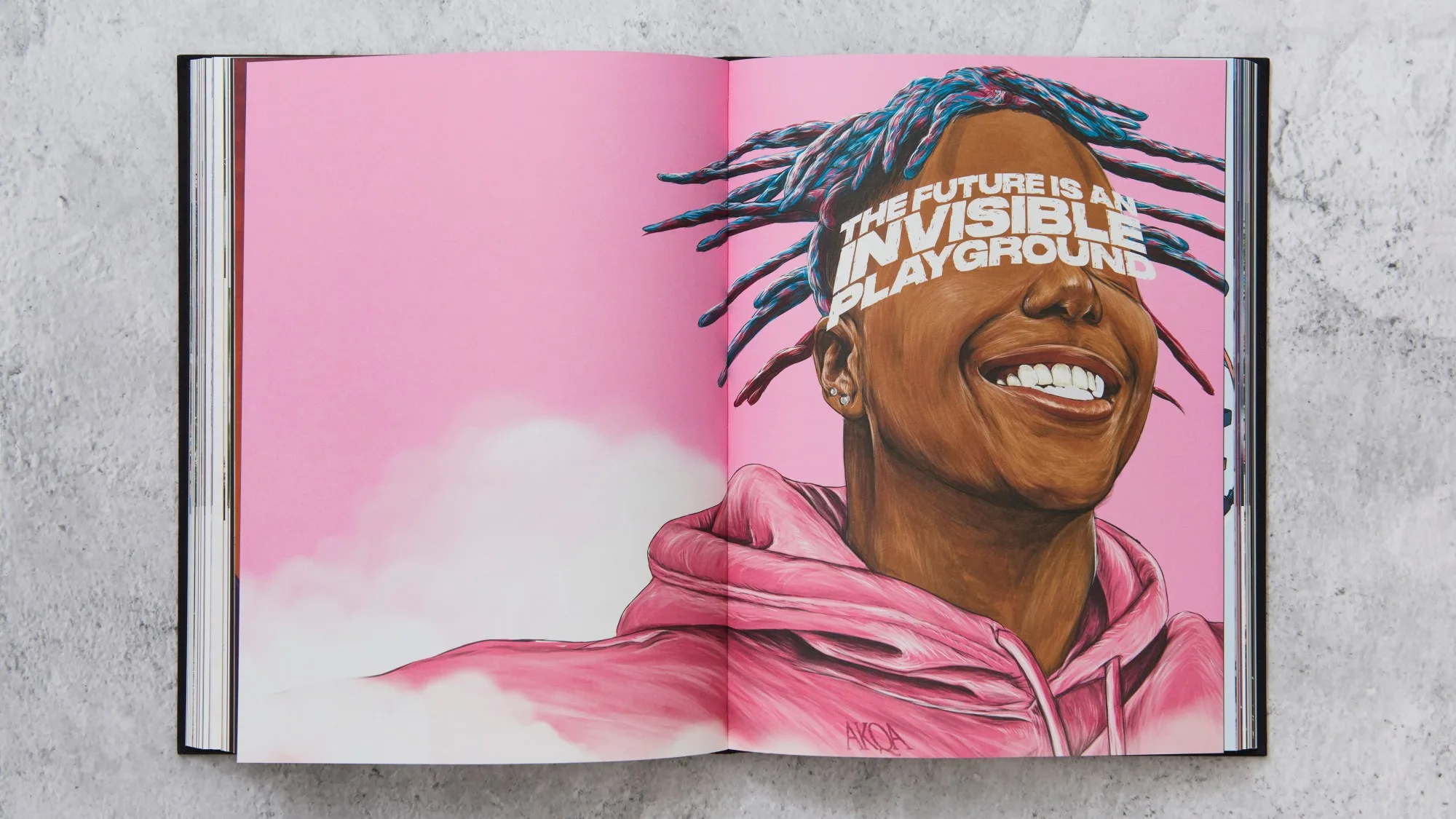 An open book shows an illustrated portrait of a smiling person with blue and pink hair and a pink hoodie, set against a pink sky background. Text reads: THE FUTURE IS AN INVISIBLE PLAYGROUND.