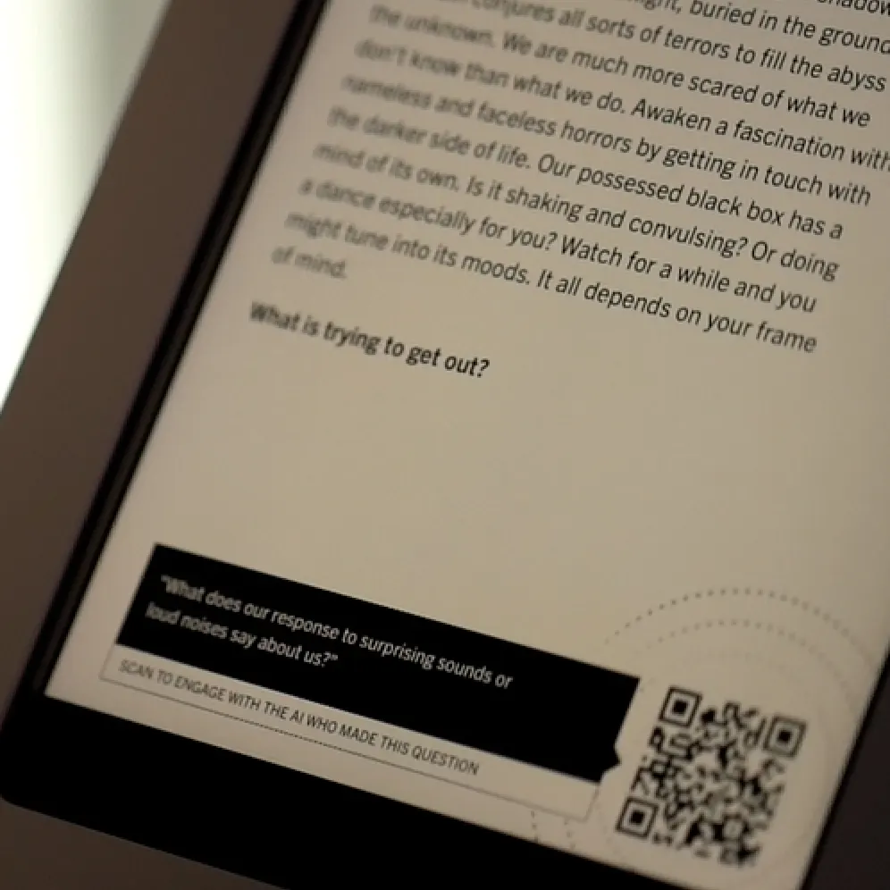 A close-up of a digital screen displaying text and a QR code, with a section highlighted in black. The visible question reads, What is trying to get out? The image is slightly out of focus at the edges.