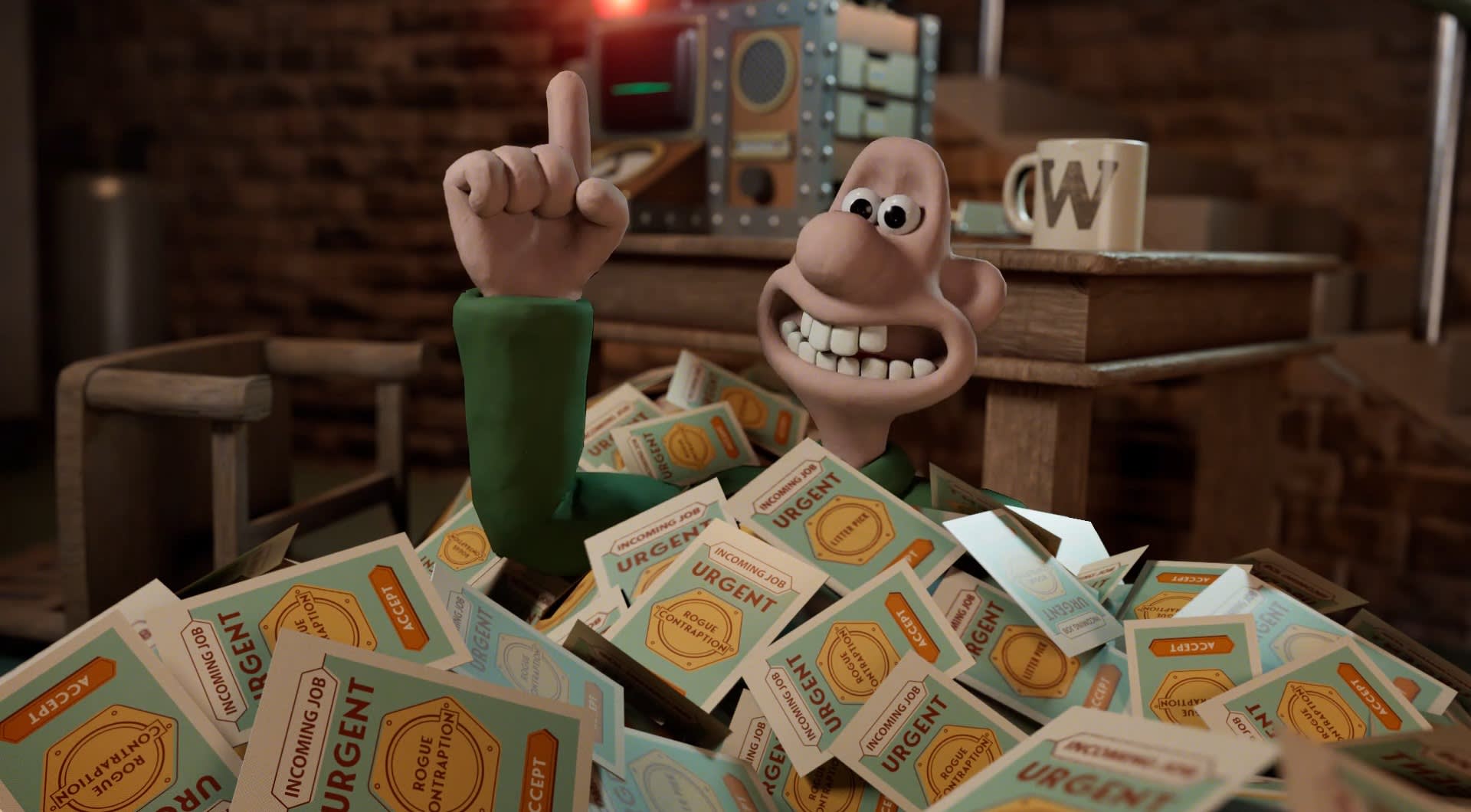 A claymation character in a green shirt sits in a pile of envelopes labeled URGENT, smiling widely and raising one finger. In the background, there’s a mug and some equipment on a wooden desk.