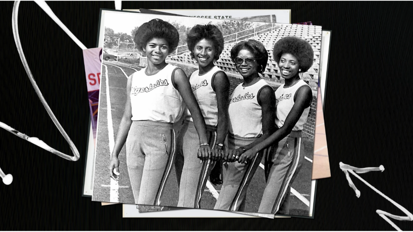 Four young women in matching athletic uniforms stand together on a track, smiling and holding a relay baton. Bleachers are visible in the background. The image appears to be from the past, in black and white.