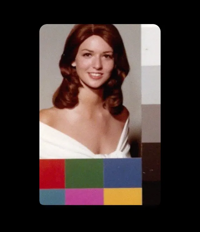 A woman with brown hair, wearing an off-shoulder white garment, smiles at the camera. She is positioned next to a grayscale color strip, with a row of colored squares at the bottom of the image.