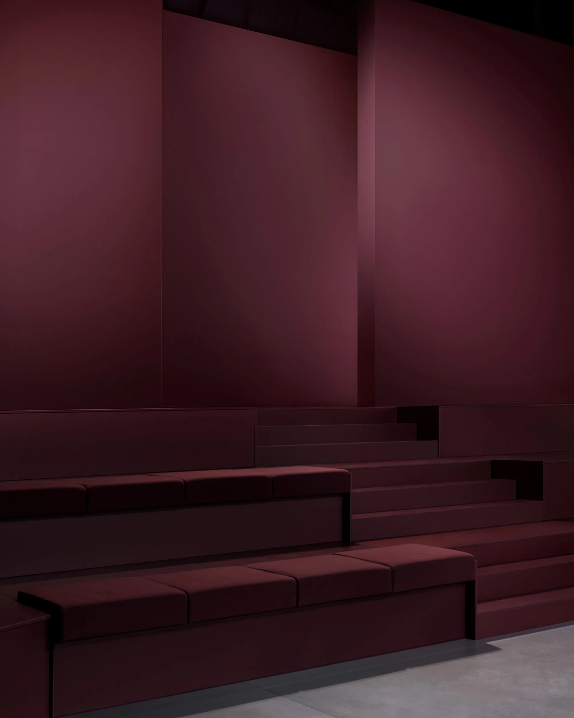 Minimalist interior with tiered maroon seating and matching maroon walls, featuring clean lines and a modern, geometric design. The lighting is soft, creating a calm and sophisticated atmosphere.