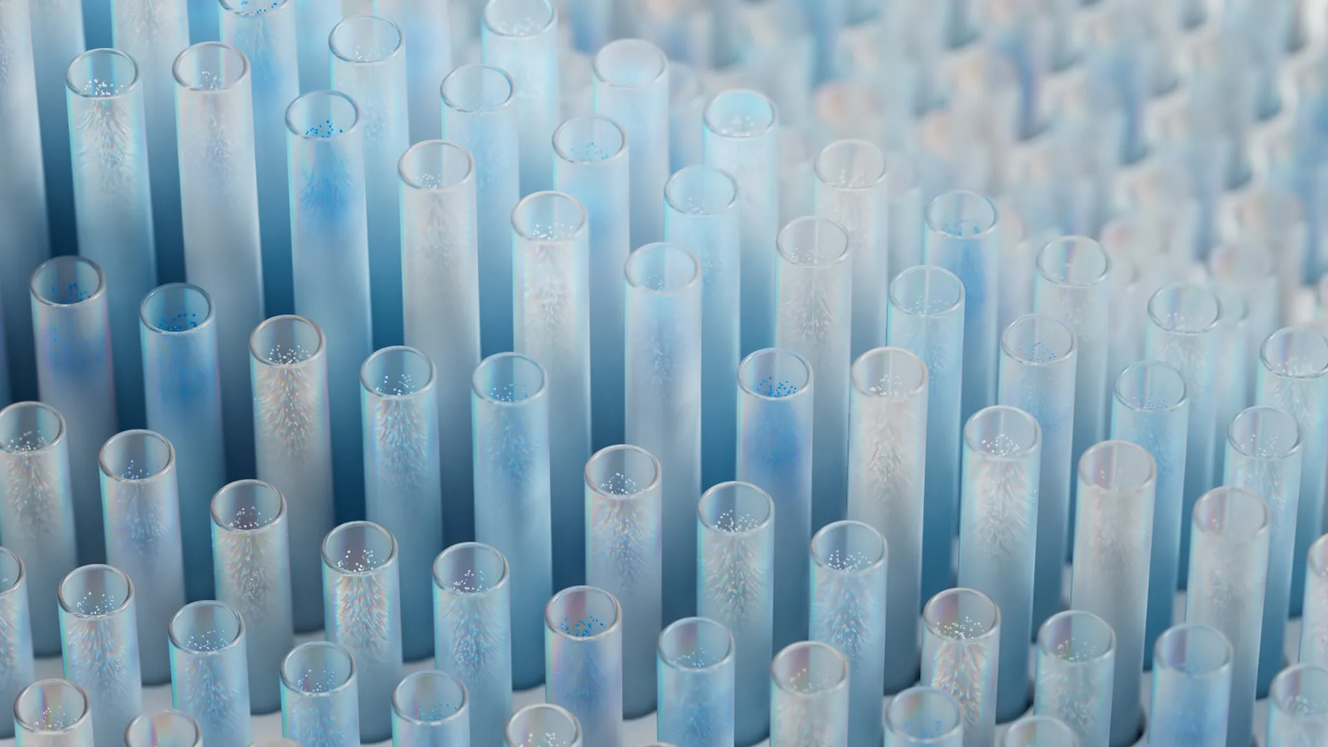 Close-up of many transparent blue cylindrical tubes standing upright, with delicate frost-like patterns inside, creating an abstract, wintery appearance.