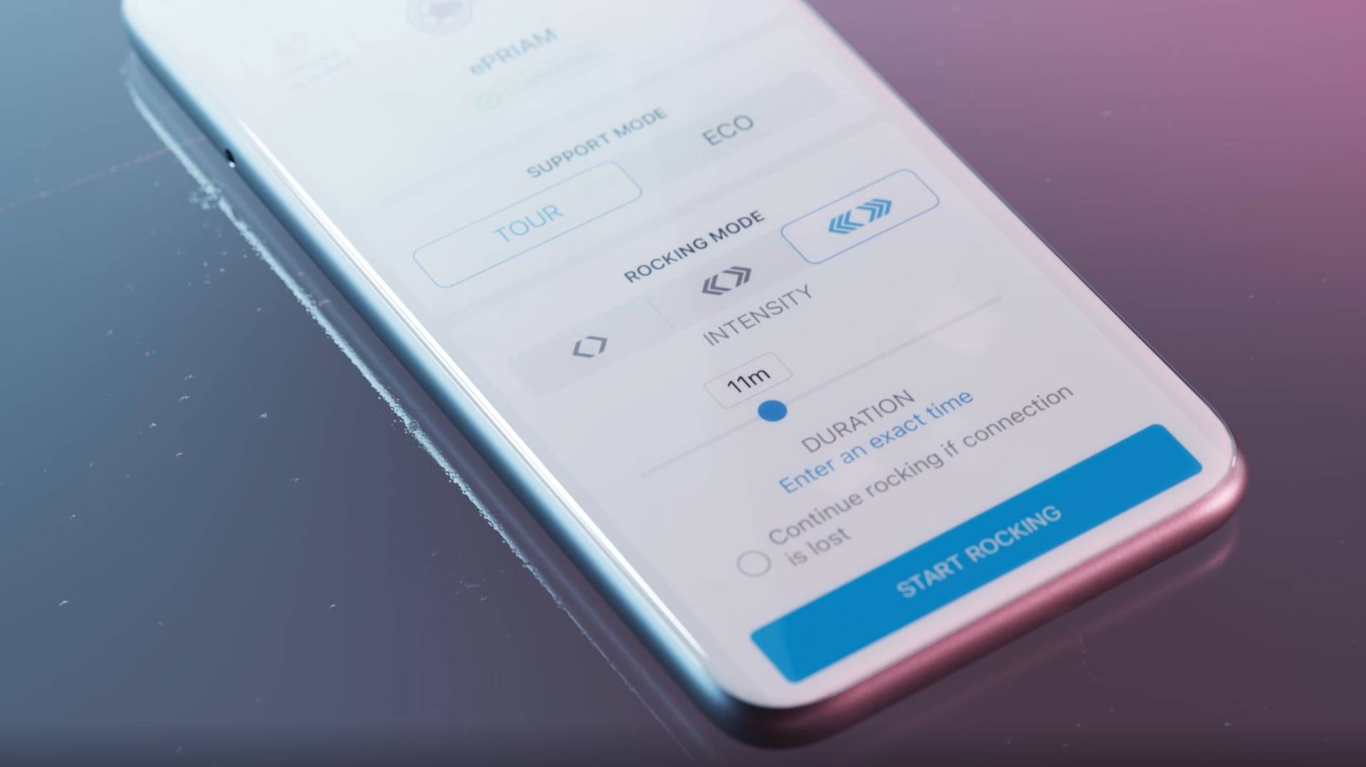 A smartphone screen displays an app interface with settings for support mode, rocking mode, intensity, and duration. A blue START ROCKING button is at the bottom. The phone rests on a glossy surface.