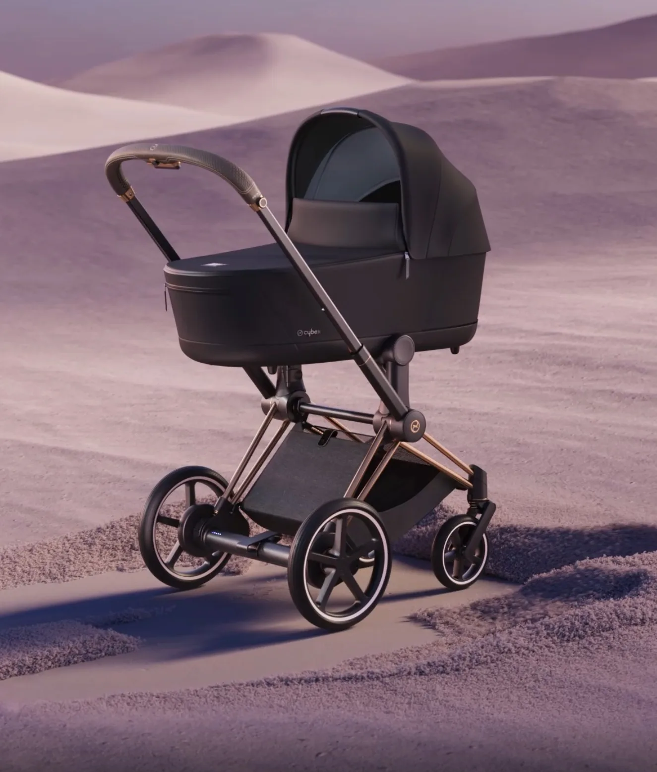 A sleek black baby stroller with gold accents is standing on a sandy surface in a pastel-colored desert landscape with soft dunes in the background.