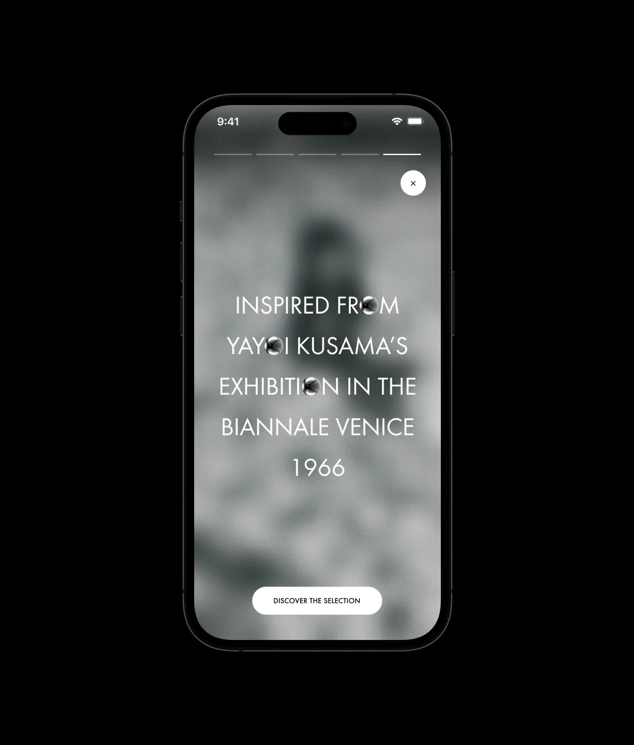 A smartphone screen displays text reading “Inspired by Yayoi Kusama’s exhibition in the Biennale Venice 1966” over a blurred grayscale background, with a button below labeled “Discover the selection.”.