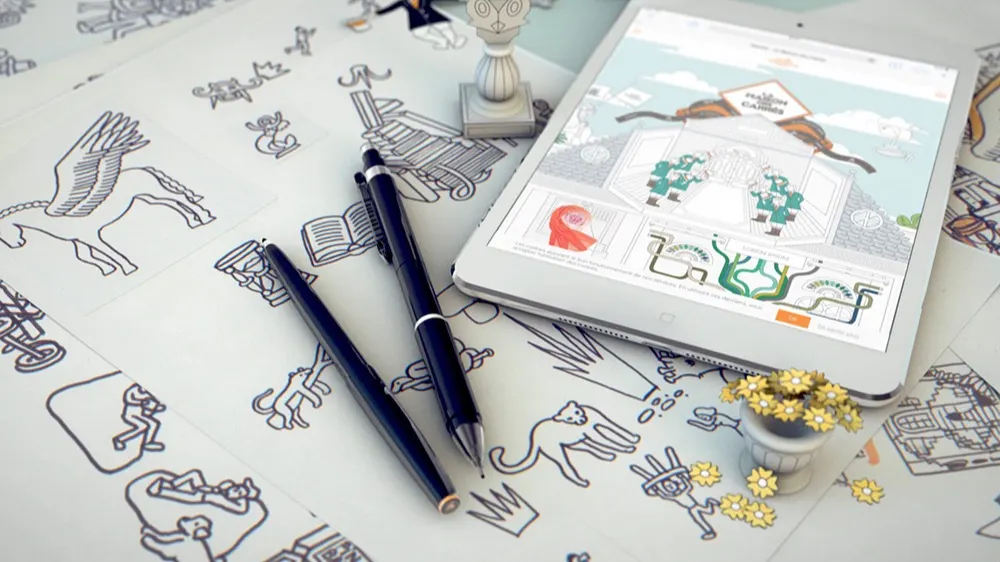 A tablet displaying a colorful fantasy illustration rests on a table covered with black-and-white line art drawings, along with pens, a chess piece, and a small pot of yellow flowers.