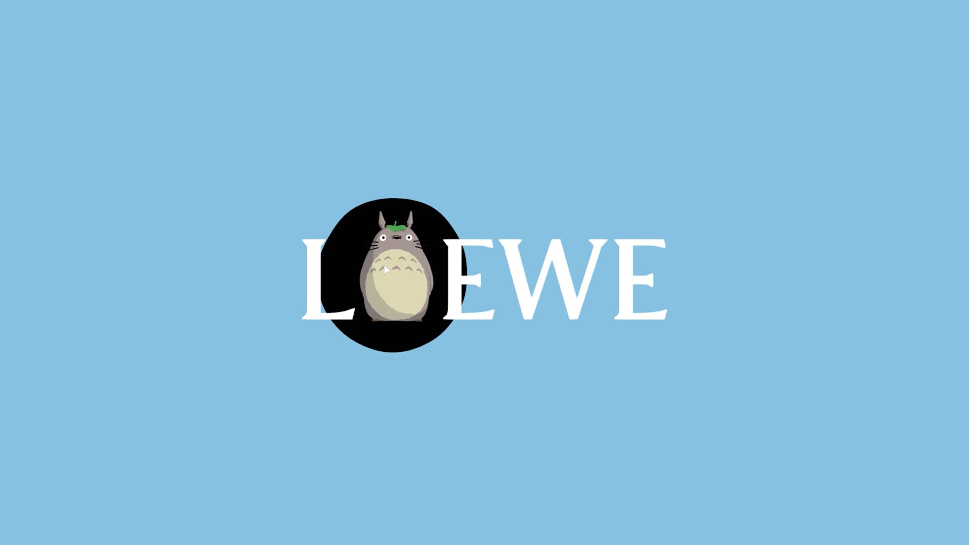 The word LOEWE on a light blue background, with the letter O replaced by a black oval featuring an illustration of Totoro, a gray and white animated character with pointy ears and a leaf on its head.