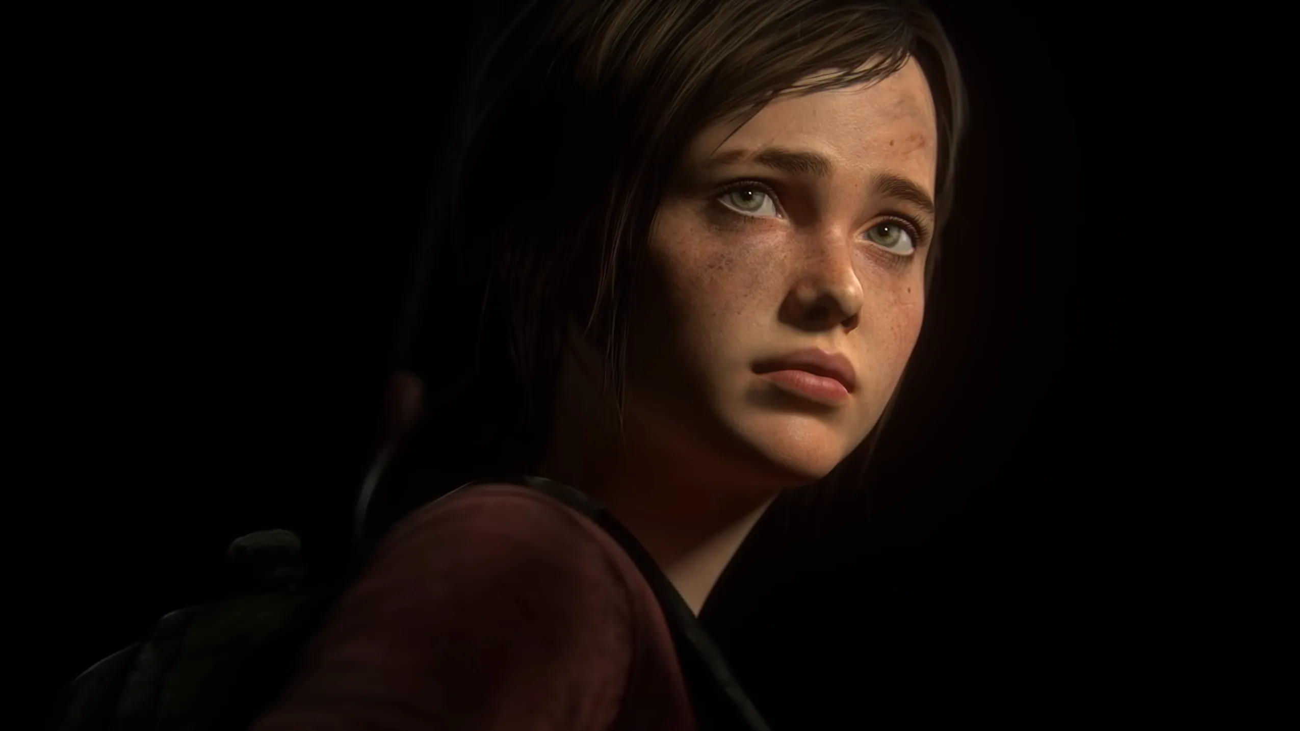 A young girl with brown hair and freckles looks upward with a worried expression, illuminated by soft light against a dark background. She wears a maroon shirt and has a backpack strap over her shoulder.