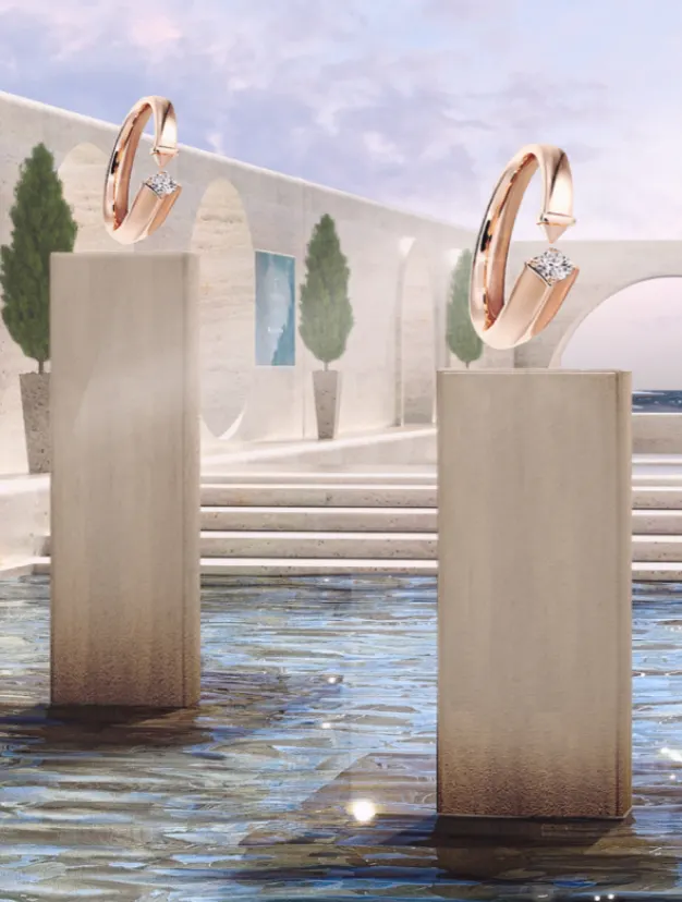 Two rose gold diamond rings are displayed on tall stone pedestals above a reflective pool, with a backdrop of an elegant courtyard featuring arched walls, potted trees, and a view of the sea under a pastel sky.