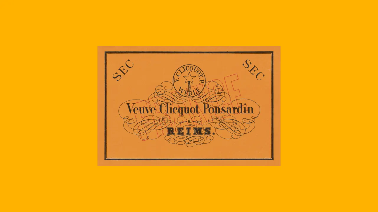 A vintage Veuve Clicquot Ponsardin champagne label with ornate black script and flourishes on an orange background, with REIMS and SEC written on the label.