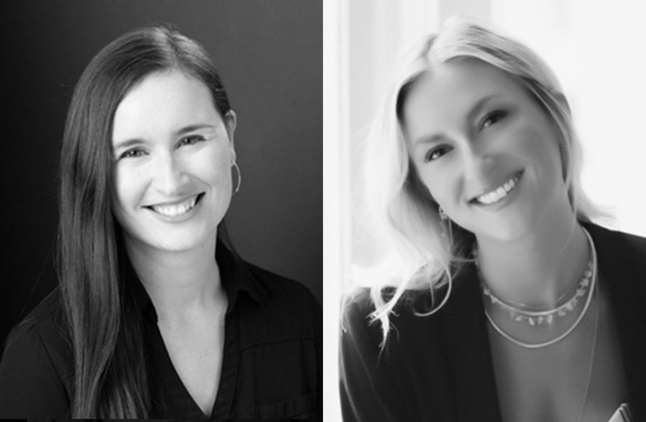 Black and white photo of two women smiling. The woman on the left has long, straight dark hair and wears a dark top. The woman on the right has light, wavy hair, wears a blazer, and is posed in front of a bright background.