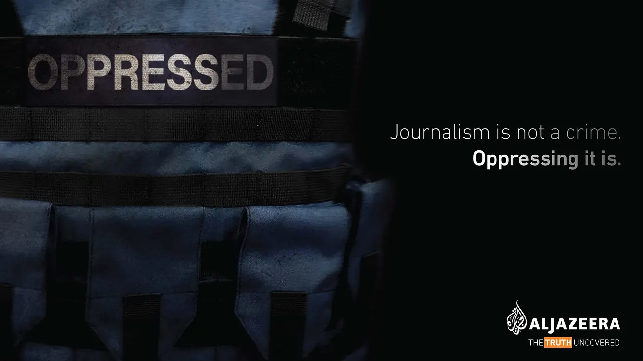 A close-up of a blue vest labeled OPPRESSED beside the text, Journalism is not a crime. Oppressing it is. Al Jazeera logo appears in the lower right corner.