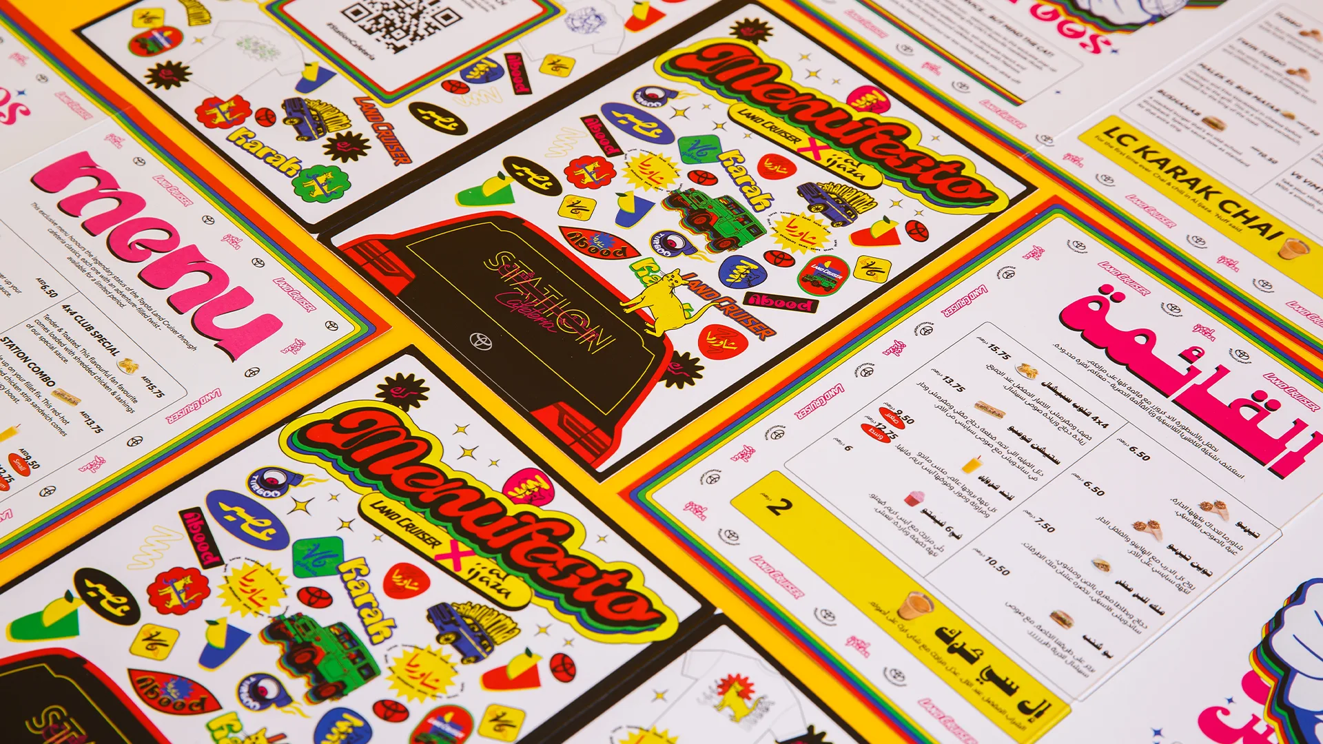 Colorful printed menus and manifestos featuring playful stickers, vibrant borders, and text in English and Arabic are arranged in a flat lay pattern on a bright yellow surface.