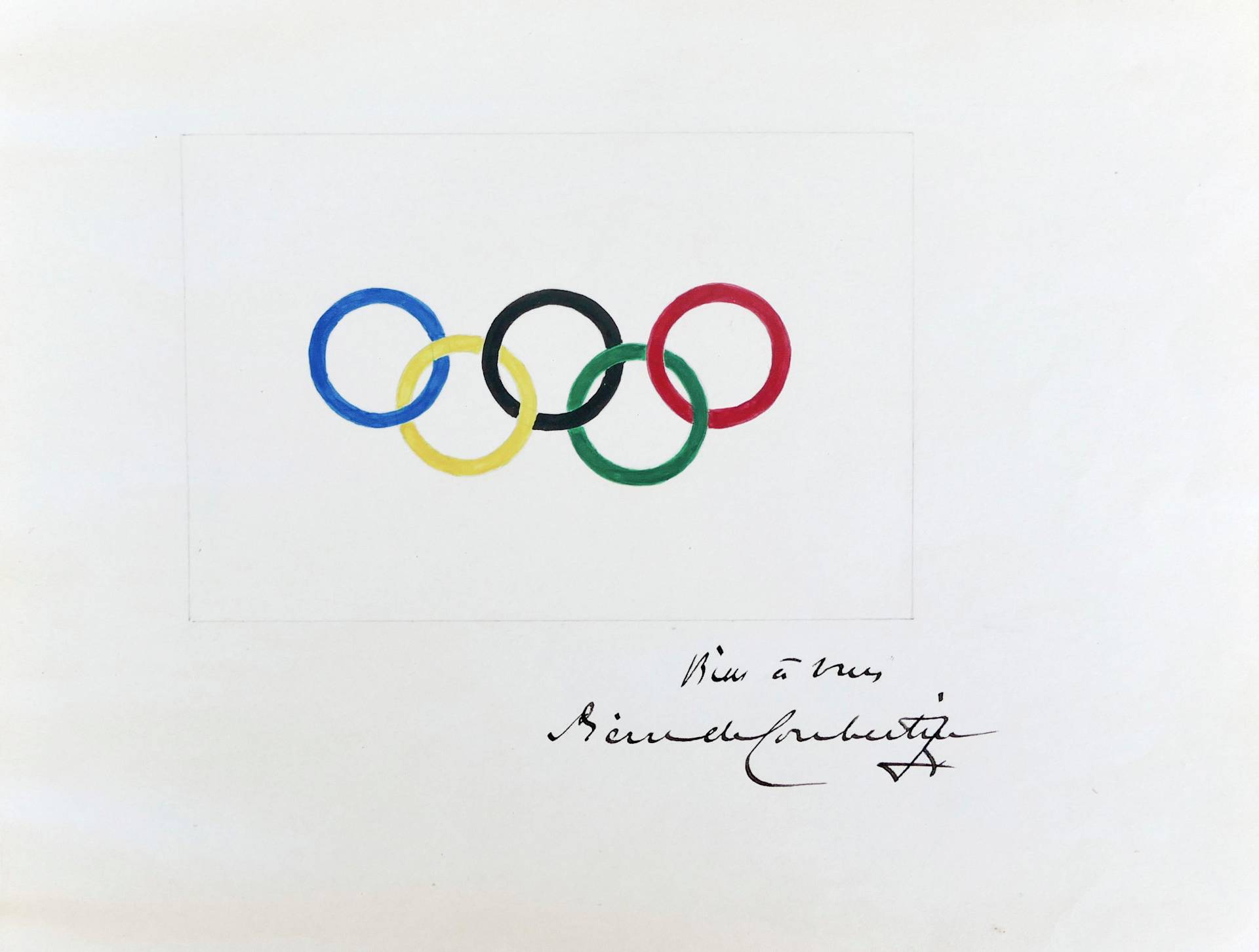 The image shows the Olympic rings in blue, yellow, black, green, and red on a white background, with a handwritten signature and note below the rings.