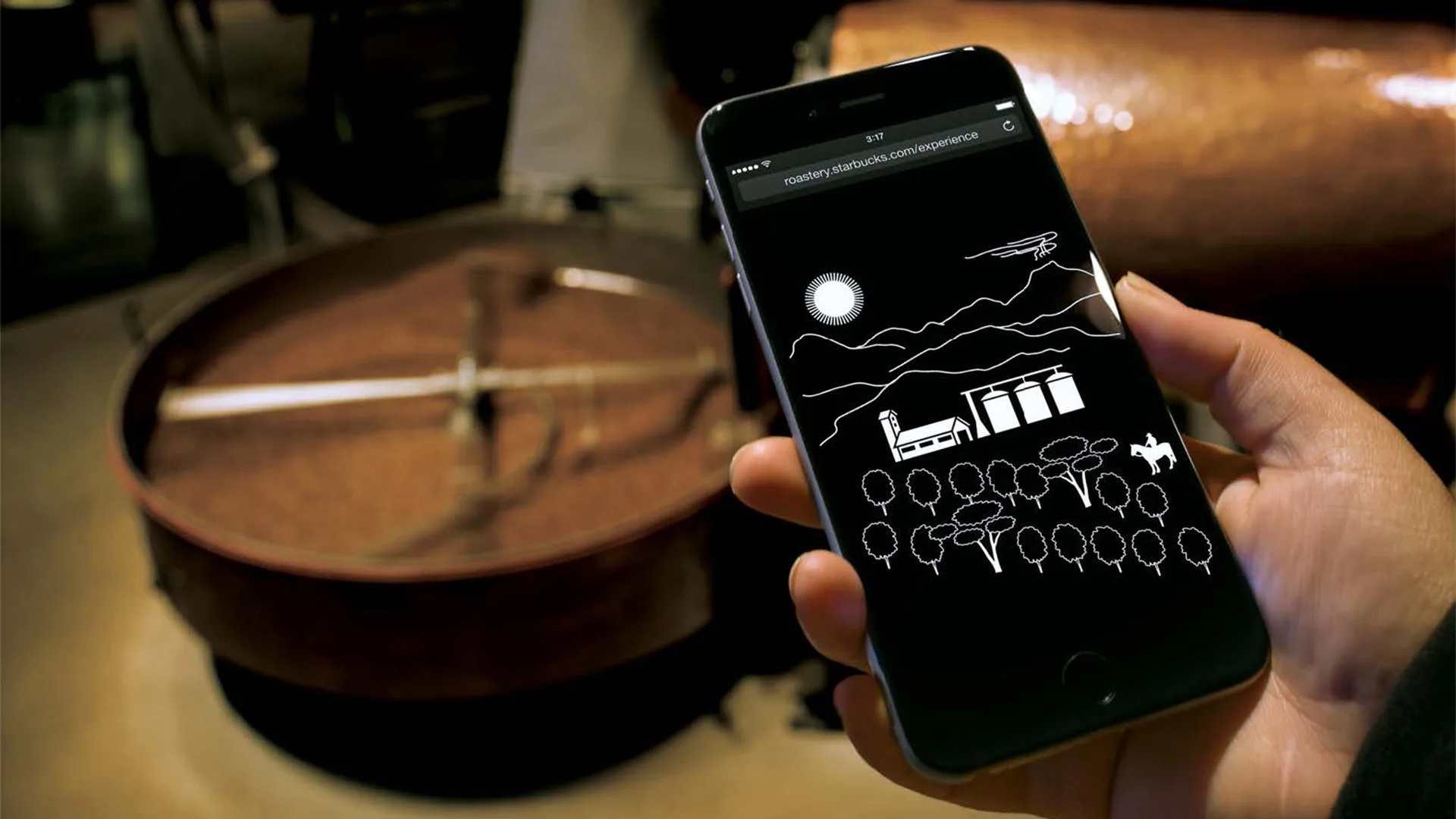 A person holds a smartphone displaying a simple white line drawing of a landscape with mountains, a factory, trees, and a horse, in front of blurred copper equipment in the background.