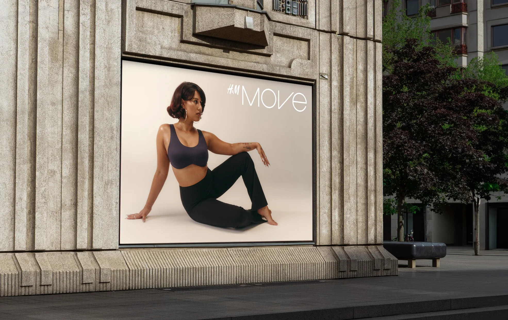 A large outdoor billboard displays a woman in activewear performing a seated yoga pose on a light background, with the text #MOVE in the upper right corner.