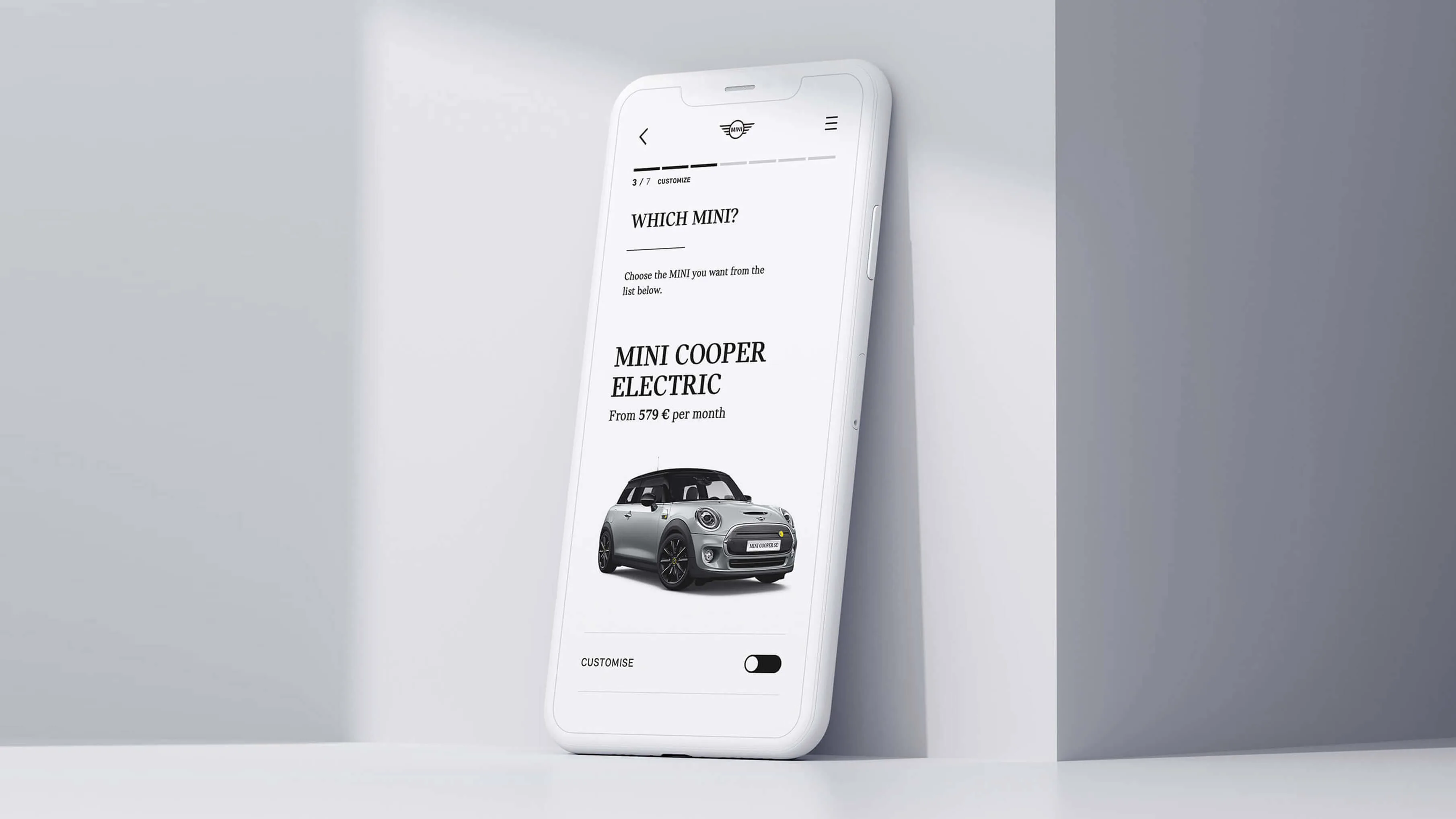 A white smartphone leans against a white wall, displaying a car selection screen featuring a MINI Cooper Electric with pricing information and a photo of the car.