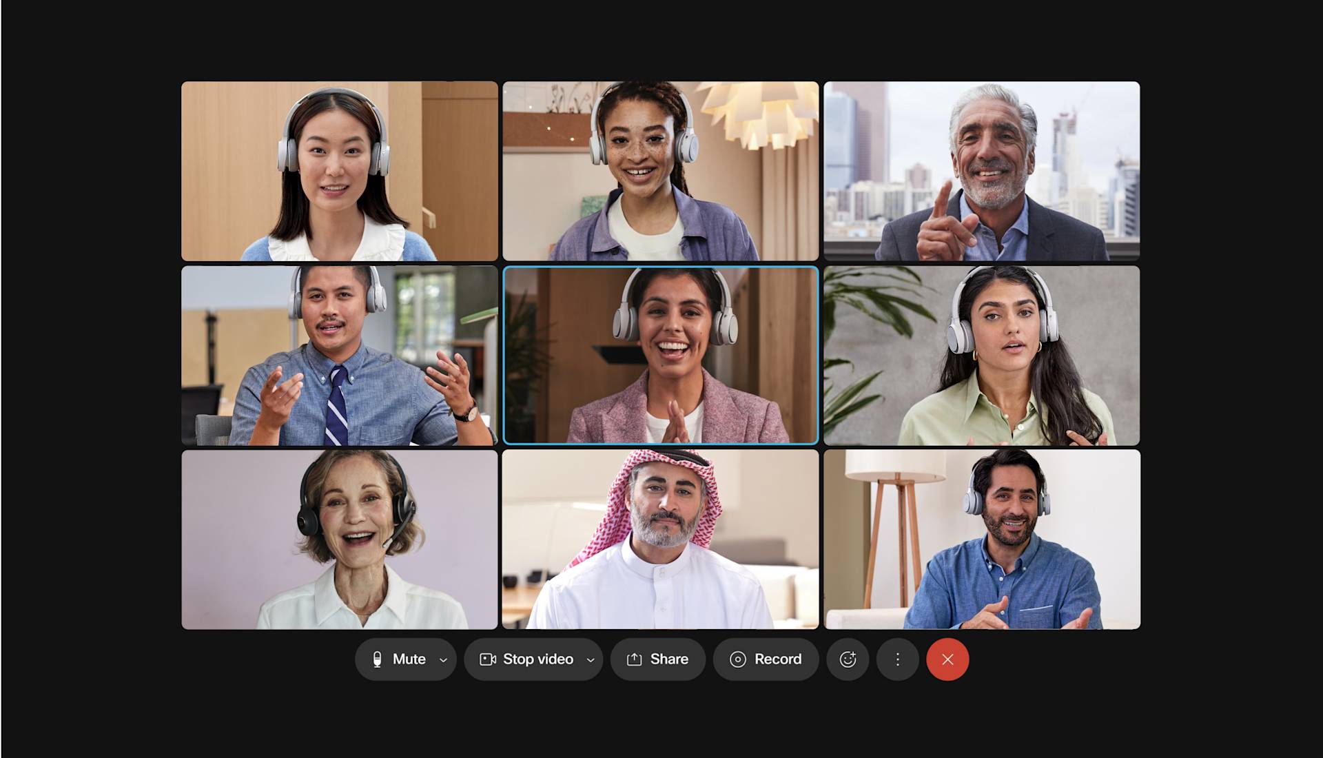 A diverse group of nine people participates in a video conference call, each visible in their own video window, smiling and engaging from different indoor locations. Meeting controls are visible at the bottom of the screen.