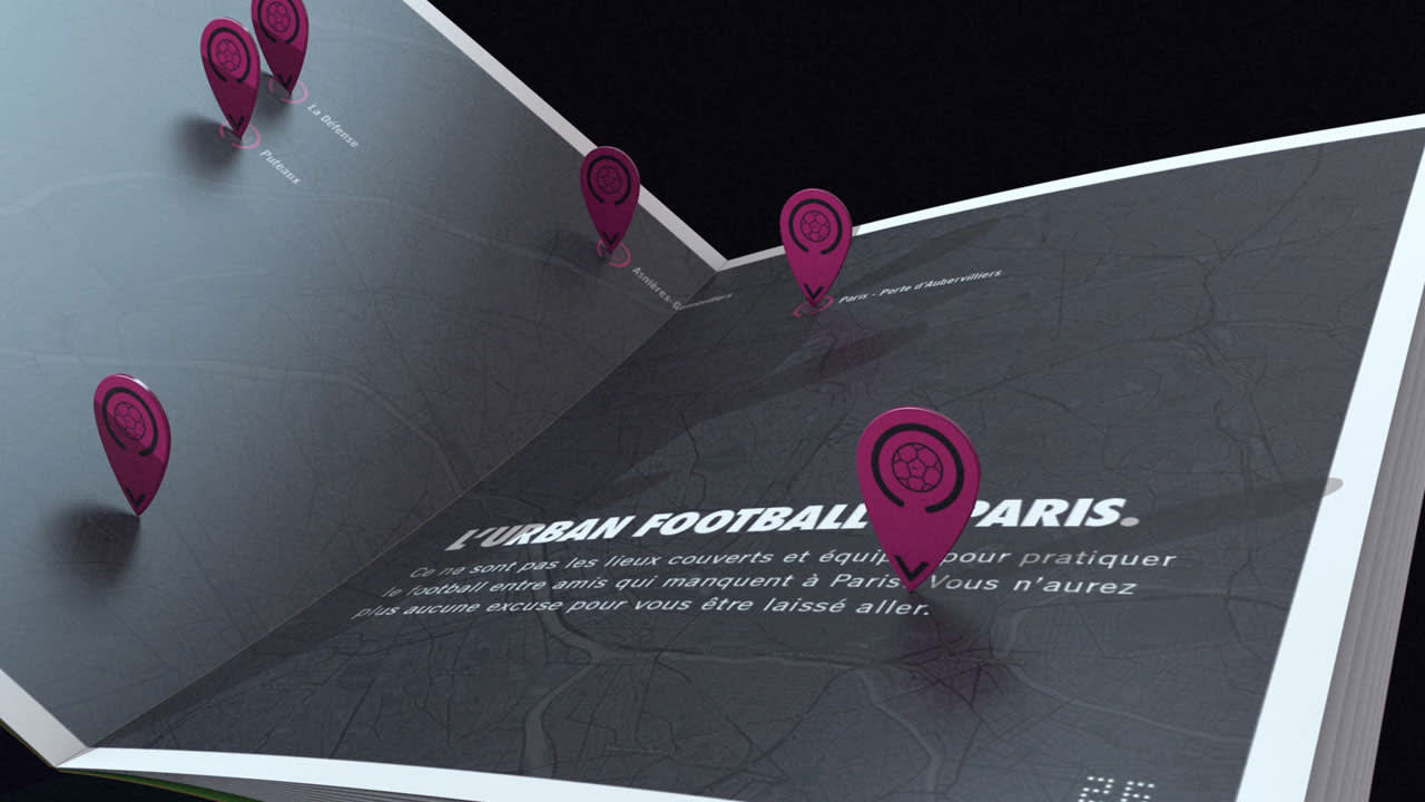 A close-up of an open book displaying a map of Paris with pink location pins marking football fields. French text on the page reads LURBAN FOOTBALL À PARIS.