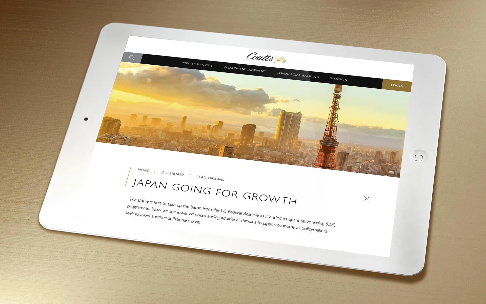 A white tablet displaying a financial news website with a cityscape of Tokyo, including Tokyo Tower, and the headline “Japan Going for Growth.” The tablet is resting on a gold-colored surface.