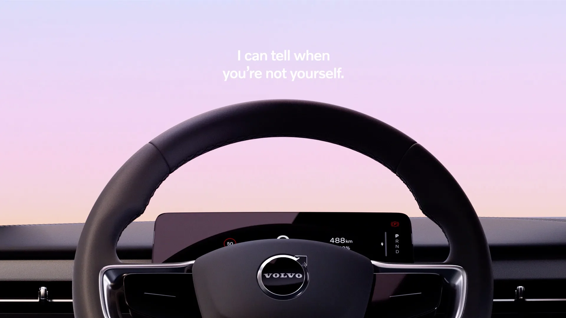 A Volvo steering wheel and digital dashboard against a purple and pink gradient background. Above the wheel, text reads: I can tell when youre not yourself.
