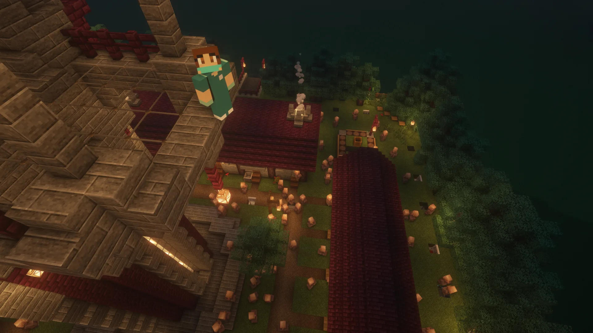A Minecraft character stands on the edge of a tall stone and brick building at night, overlooking a lit-up village with red-roofed houses and scattered lanterns among trees.