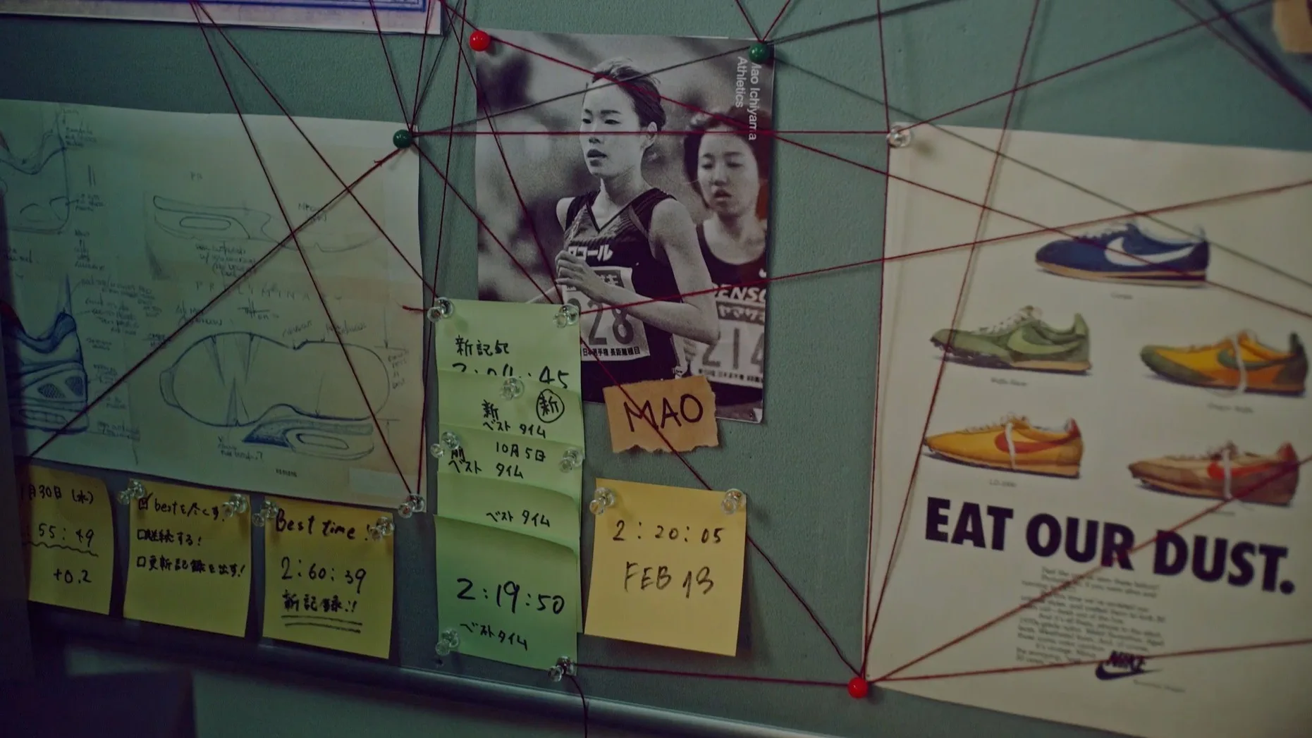 A bulletin board displays a running map, notes with race times, a photo of two female runners, and a shoe advertisement reading EAT OUR DUST. Red string connects the items in a web-like pattern.