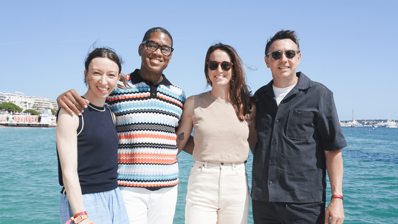 Gemma Redgrave, Tye Comer, Chloe Wix and Sam Kelly. standing side-by-side outdoors with a bright blue sky and ocean in the background.