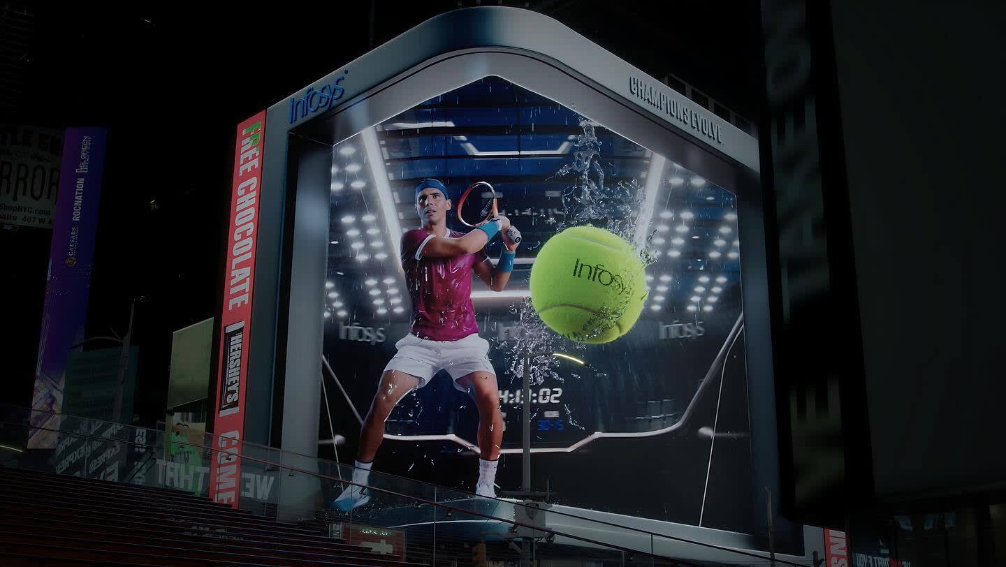 A large digital billboard in a city displays a tennis player in action with a racket and a giant tennis ball, surrounded by dynamic splashes and lights, promoting the brand “Infosys.”.