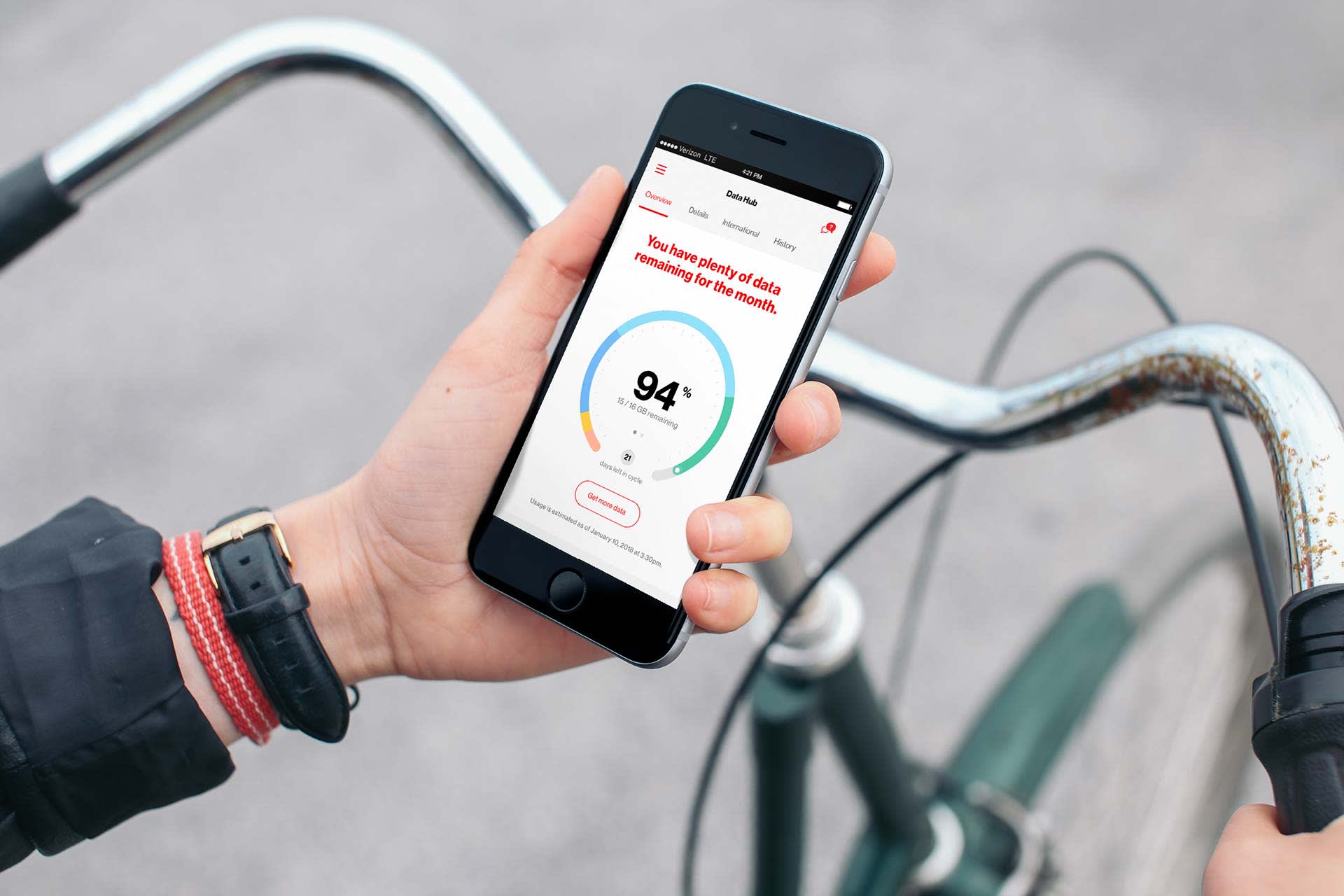 A person holding a smartphone showing a health app with a circular progress bar at 94%, standing next to a bicycle and gripping the handlebars with their other hand.