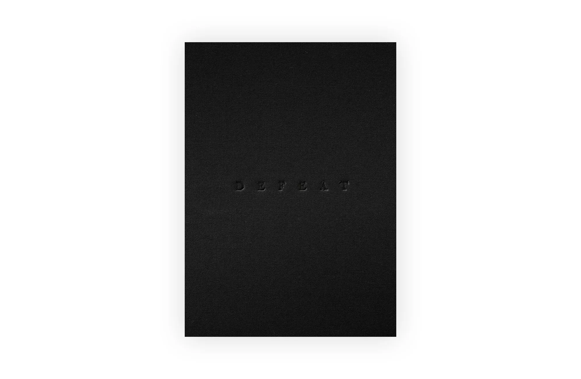 A black textured surface with the word DEFEAT embossed in the center, blending subtly into the background.