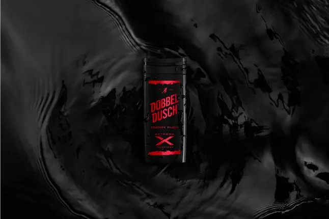A black bottle of Dobbel Dusch Energy Plus shower gel with red labeling lies on a dark, rippling liquid surface, creating a dramatic and intense atmosphere.
