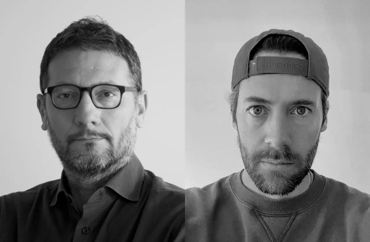 Side-by-side black and white portraits of two men: the left man has short hair, glasses, a beard, and a collared shirt; the right man has a beard, wears a backward cap and a crewneck sweatshirt.