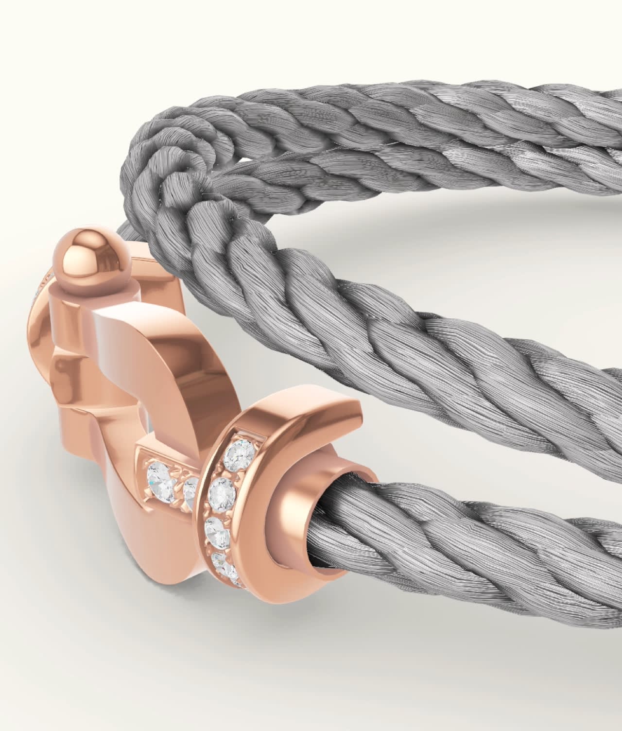 A close-up of a gray braided rope bracelet with a rose gold clasp, adorned with small, sparkling diamonds. The clasp is elegantly designed and secures the rope ends together.