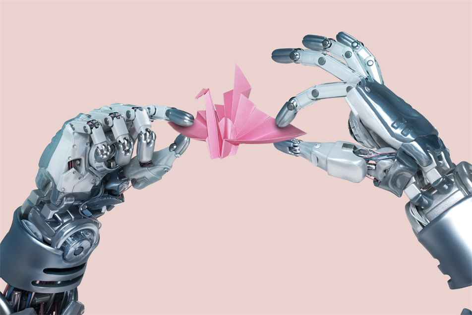 Two robotic hands delicately hold a pink origami crane between their fingers, set against a pale pink background.